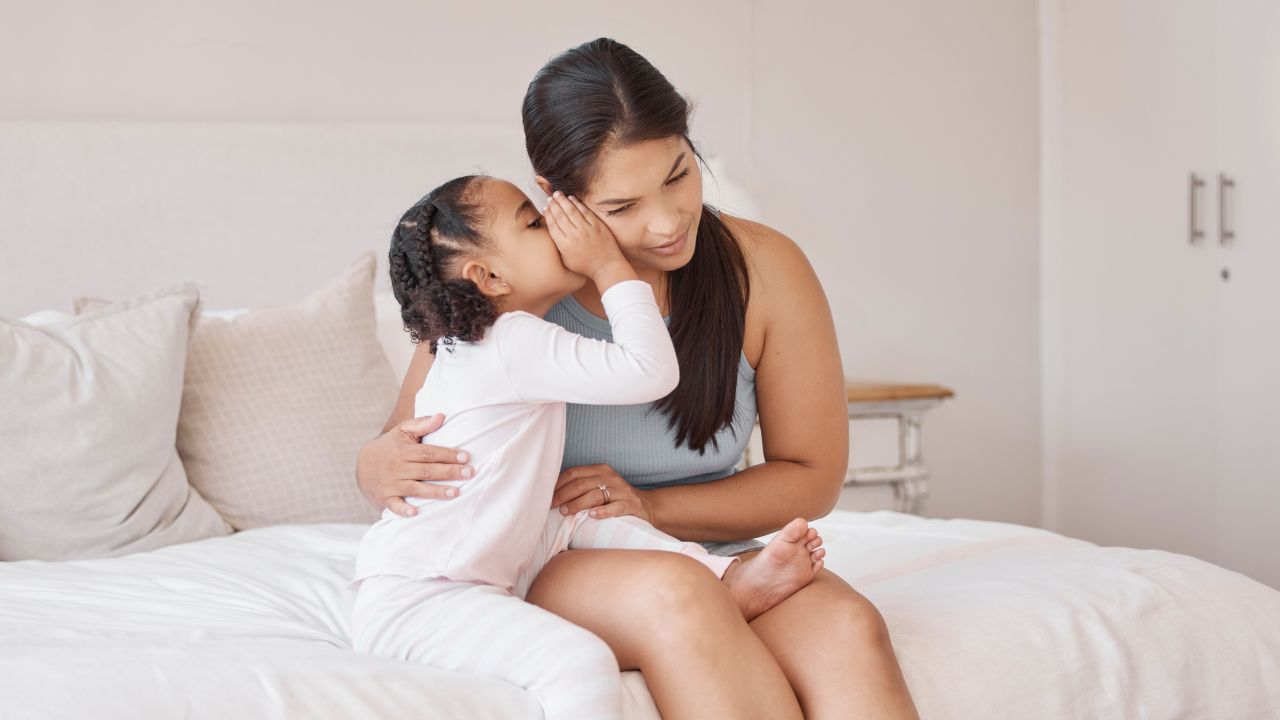 Kids whisper secret in mom ear in home bedroom for trust, love and confidential talk.
